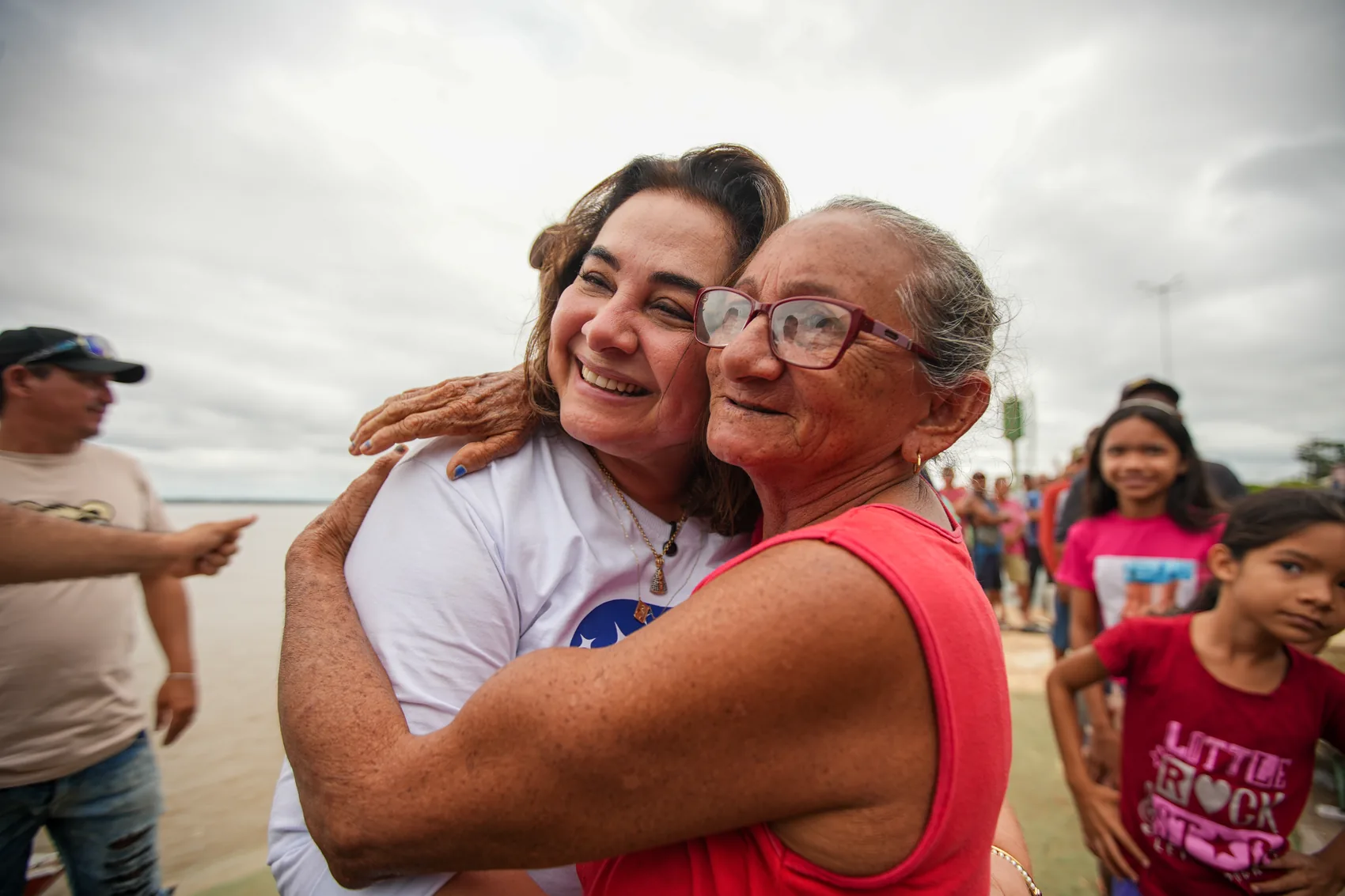 Professora Maria abraçada com uma senhora na beira do rio